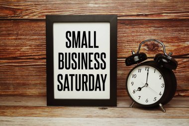 Ahşap zemin üzerinde alarm saati olan küçük işletme cumartesi metni