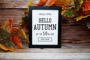 Merhaba sonbahar indirimi% 50 indirimli metin ve ahşap arka planda akçaağaç yaprağı süslemesi