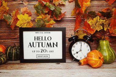 Hello Autumn İndirim% 20 indirimli alarm saati ve ahşap arka planda akçaağaç yaprağı süslemesi