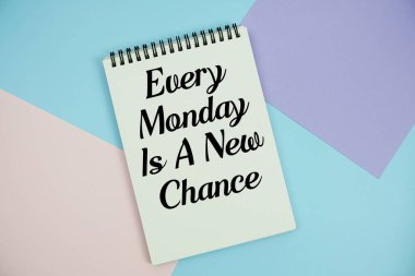 Her Pazartesi Not Defteri üzerine yazılmış Yeni Bir Şans metni çok renkli pastel arka planda yatar