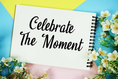 Not defterine yazılan ve çiçek süslemeleriyle birlikte çok renkli pastel arka planda uzanan Anı kutla