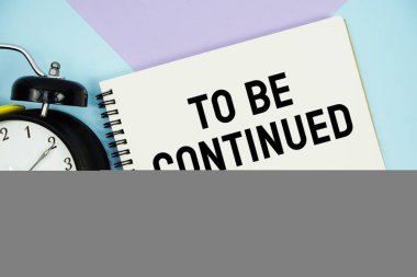 Not defterinde alarmlı saatin düz olduğu metne devam etmek için çok renkli pastel arkaplan üzerine yatın