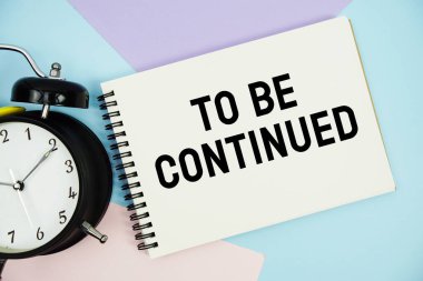 Not defterinde alarmlı saatin düz olduğu metne devam etmek için çok renkli pastel arkaplan üzerine yatın