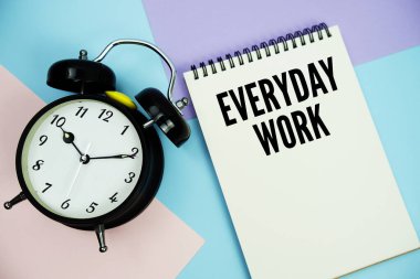 Alarm saatinin düz olduğu not defterine yazılan günlük çalışma metni çok renkli pastel arka planda yatıyordu