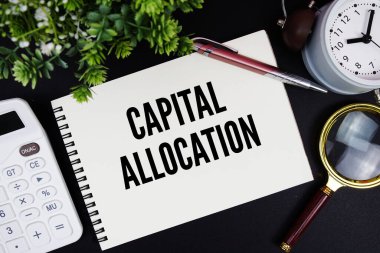 Alarm saati, büyüteç ve siyah arkaplanda hesap makinesi ile not defterine yazılan büyük harf tahsis metni