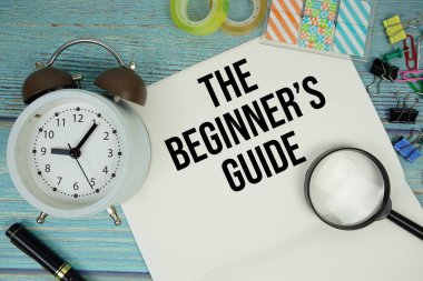 Acemi Rehberi, ofisin etrafını saran kağıdın üzerindeki metinde bir büyüteç ve mavi ahşap bir yüzey üzerindeki bir saat bulunur.