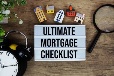 Ev modeli, büyüteç ve ahşap zemin üzerindeki alarm saatiyle ışık kutusunda nihai ipotek listesi metni