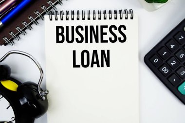 Not defterine hesap makinesi ve alarm saati ile yazılmış iş kredisi metni