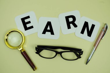 Sarı zemin üzerinde büyüteç, gözlük ve kalem olan EARN alfabesi harfleri