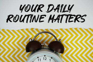 Günlük rutin metinleriniz kağıda yazıldı. Alarm saati düz, sarı simge arkaplanda yatıyordu.