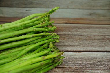 Ahşap arka planda bir sürü taze kuşkonmaz var.