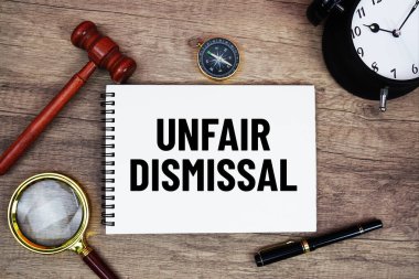 Not defterine ahşap tokmak ve büyüteçle yazılmış haksız işten çıkarma mesajı ahşap arka planda yatıyordu.