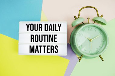 Günlük rutininiz Meseleler ışık kutusunda, pastel arka planda alarm saati olan metinleriniz