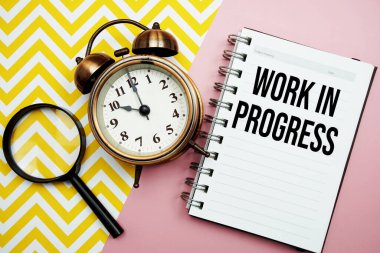 Alarm saati ve büyüteçle not defterine yazılan çalışma süreci metni