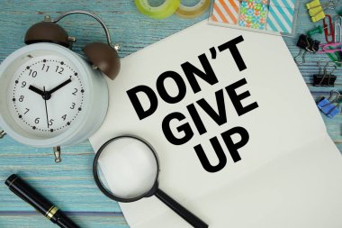 Not defterine alarm saati ve büyüteçle yazılmış metinden vazgeçme. Ahşap zemin üzerinde yatıyordu.