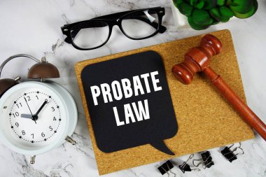 Alarm saati ve mermer zemin üzerinde ahşap tokmak ile konuşma baloncuğu üzerine Vasiyet Kanunu metni