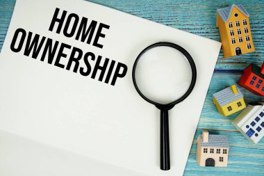 Üzerinde büyüteç ve ahşap arka planda ev modeli olan 