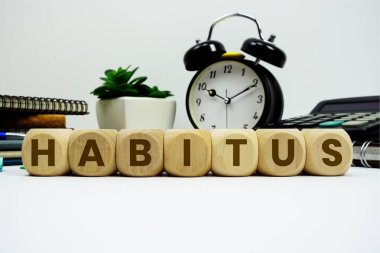 Beyaz zemin üzerinde alarm saati ve hesap makinesi olan HABITUS alfabesi harfleri