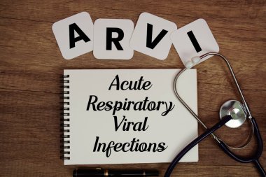 ARVI Akut Solunum Viral Enfeksiyonları metni not defterine steteskop ile ahşap arka planda yazıldı