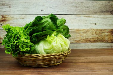 Taze çiğ Iceberg, Romaine ve Green Cos marulları bambu sepetinde ahşap arka planda