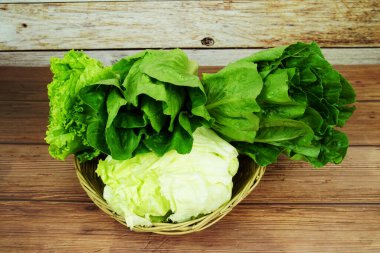Taze çiğ Iceberg, Romaine ve Green Cos marulları bambu sepetinde ahşap arka planda