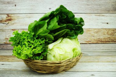 Taze çiğ Iceberg, Romaine ve Green Cos marulları bambu sepetinde ahşap arka planda