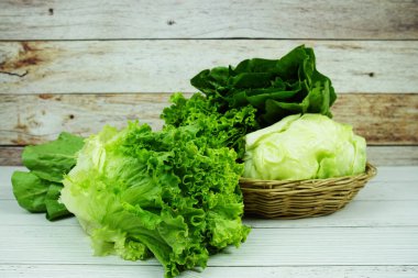 Taze çiğ Iceberg, Romaine ve Green Cos marulları bambu sepetinde ahşap arka planda