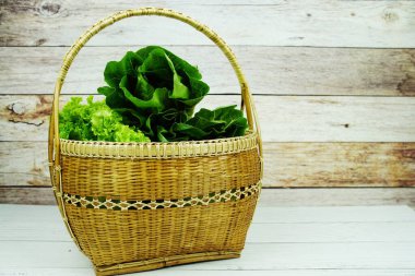 Taze çiğ Iceberg, Romaine ve Green Cos marulları bambu sepetinde ahşap arka planda