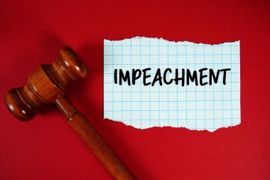 IMPEACHMENT kırmızı zemin üzerinde ahşap yargı tokmağı ile yırtık kağıt üzerine yazılmış metin