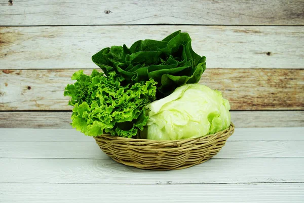 Taze çiğ Iceberg, Romaine ve Green Cos marulları bambu sepetinde ahşap arka planda