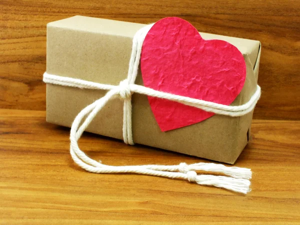 Caja de regalo envuelta en papel reciclado con cuerda blanca y etiqueta de papel rosa corazón — Foto de Stock