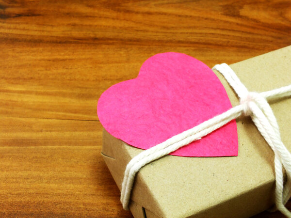 gift box wrapped in recycled paper with white rope and pink heart paper tag