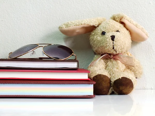 stack of notebook with sun glasses and rabbit doll