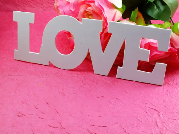 Cartão postal com flores artificiais e etiqueta com palavras com amor — Fotografia de Stock