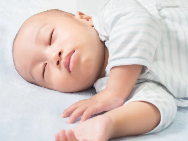 Spící dítě na zádech na bílé posteli — Stock fotografie