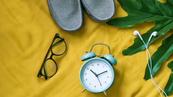 Alarm saati yaprağı dizüstü bilgisayar kulaklıkları parlak sarı bir arka planda.