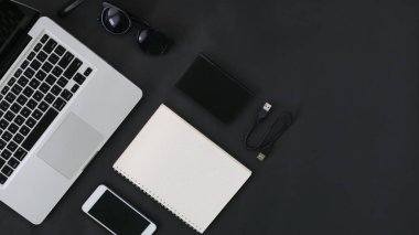 Top View laptop hardrive smartphone eyeglass notebook on black background  