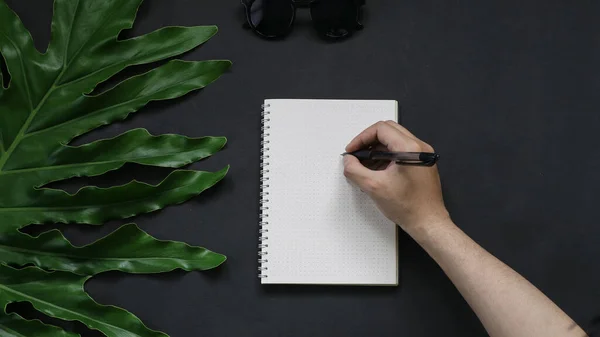 hand with sketch book on black background