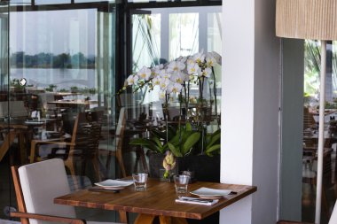 Hochiminh City, Vietnam - June 7, 2015: a restaurant elegant European-style city in HoChiMinh, with pots of white Phalaenopsis orchids Beside dinner table