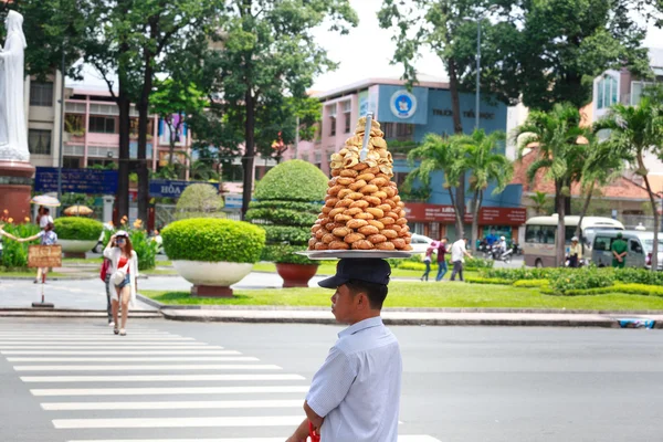 Hochiminh City, Vietnam - 14 juillet 2015 : Inconnu, un vendeur de beignets porte un plateau rempli de beignets dans la rue de Saigon avec son chapeau — Photo