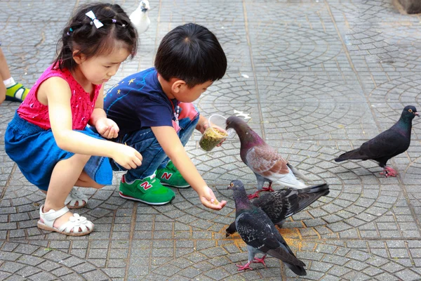 Ciudad de Hochiminh, Vietnam - 14 de julio de 2015: alimentación de palomas en manos de un niño en las calles de Saigón — Foto de Stock