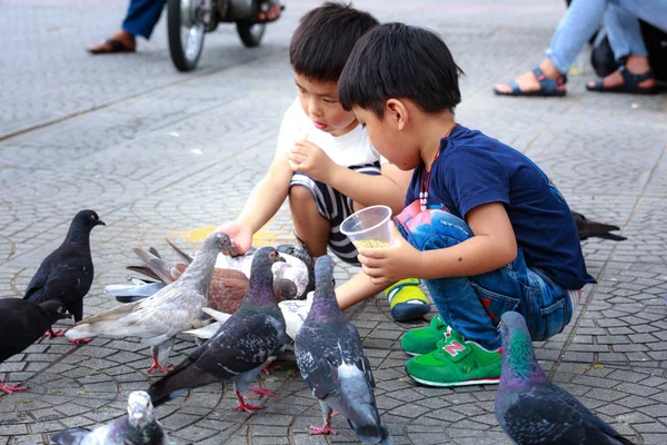 Ciudad de Hochiminh, Vietnam - 14 de julio de 2015: dos bebés para alimentar palomas en las calles de Saigón — Foto de Stock