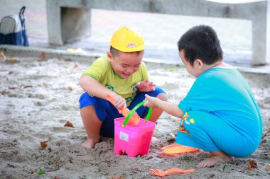Hochiminh City, Vietnam - June 21, 2015: Unknown, two cute little boys playing in the sand at the city park HoChiMinh, Vietnam