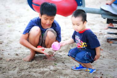 Hochiminh City, Vietnam - June 21, 2015: Unknown, two cute little boys playing in the sand at the city park HoChiMinh, Vietnam