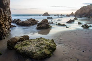 Malibu, California 'daki El Matador Eyalet Parkı' nda bulutlu kayalık plaj günbatımı.