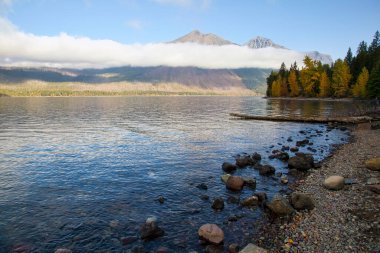 Alçak bulutlar tabakası güneş doğduktan kısa bir süre sonra Montana 'daki Buzul Ulusal Parkı' ndaki McDonald Gölü 'nde dramatik bir sahne oluşturuyor..
