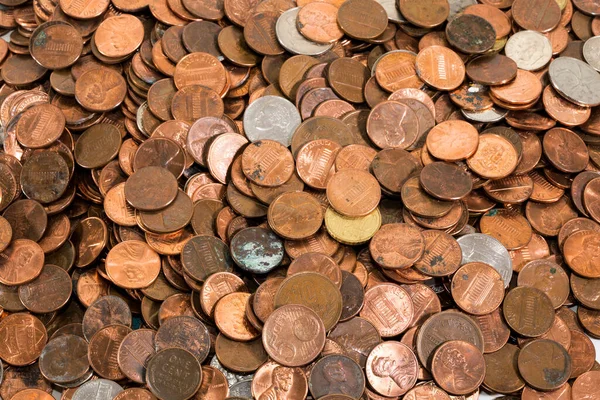Overhead closeup of a large, deep pile of many old, dirty coins. Mostly American pennies, with a few other denominations and the odd international coin tossed in.