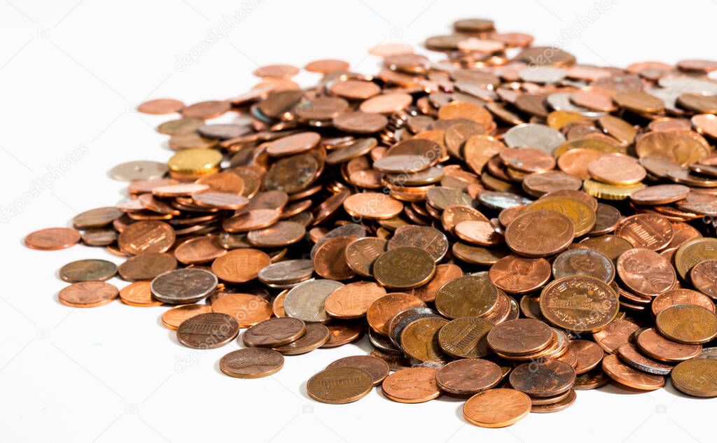 A large pile of old, dirty coins - mostly American pennies - on a clean white surface under bright lighting. Shallow macro depth-of-field shows the nearest coins in sharp focus, with farther coins gradually fading from clear view.