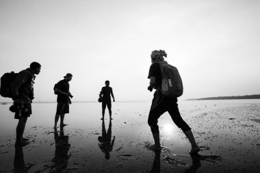 Tropikal günbatımında üç ayaklı bir fotoğrafçının silueti.