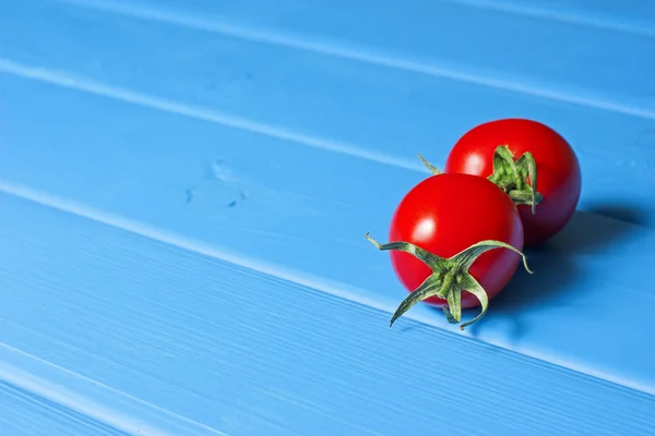 Verse tomaten op het blauwe houten tafel — Stockfoto